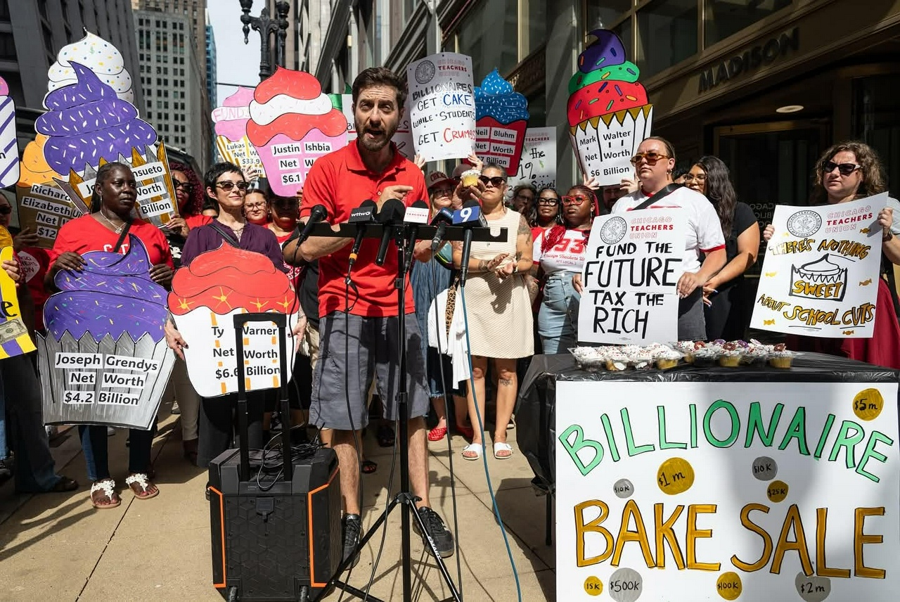 A group of people hold a press conference with large cupcake signs