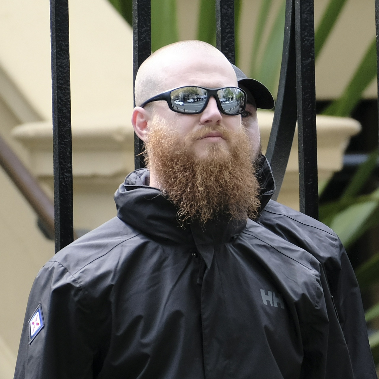 Jacob Cooper, a tall white man with straggly ginger beard, shaved head and speed dealer sunnies.