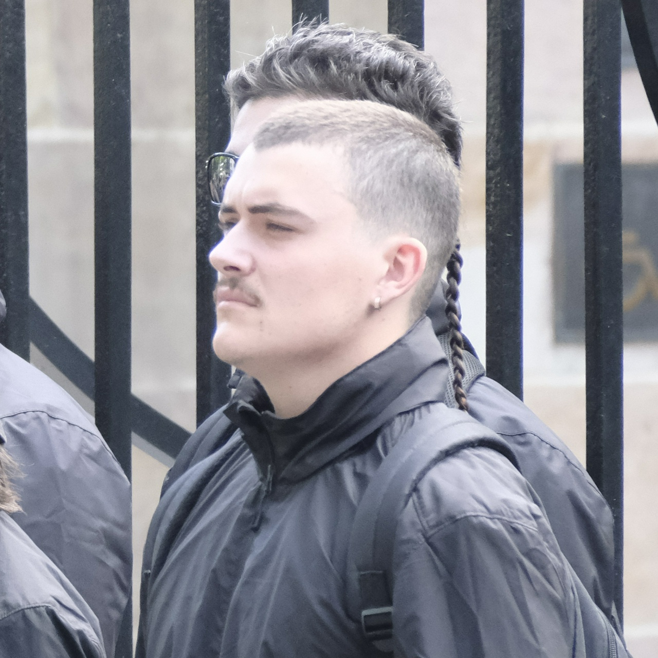 The same man from side-on, showing his single braid on the back of his otherwise shaved head