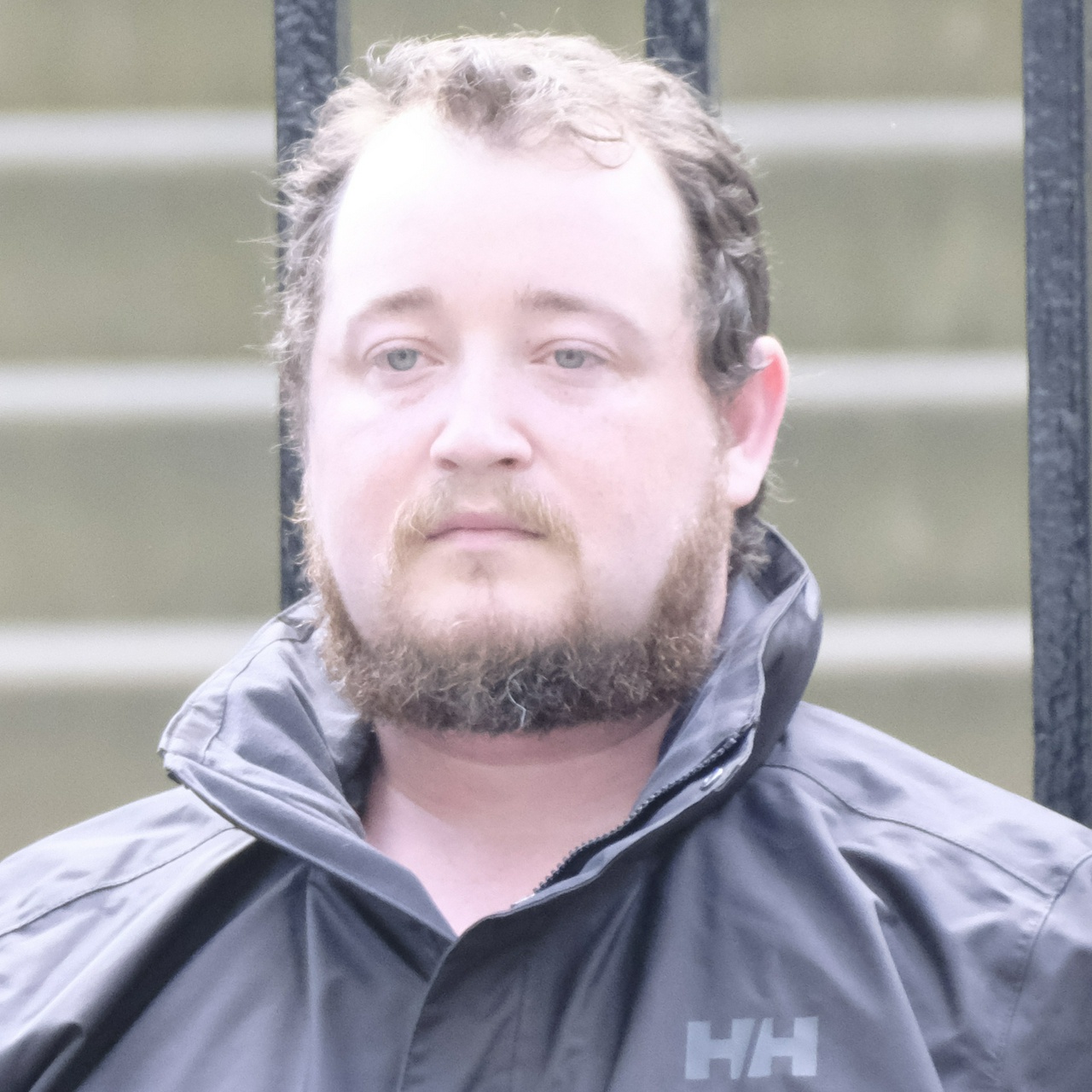 A fat guy with heavy eye bags and straggly hair & beard looking genuinely unhappy to be there