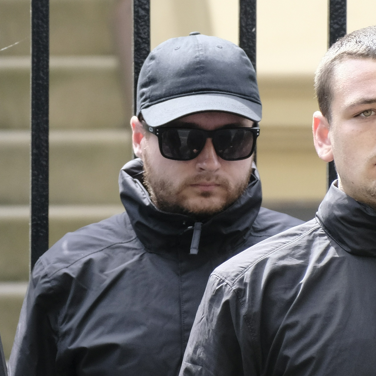 A man with unkempt facial hair, a hat and sunnies, and a small mouth