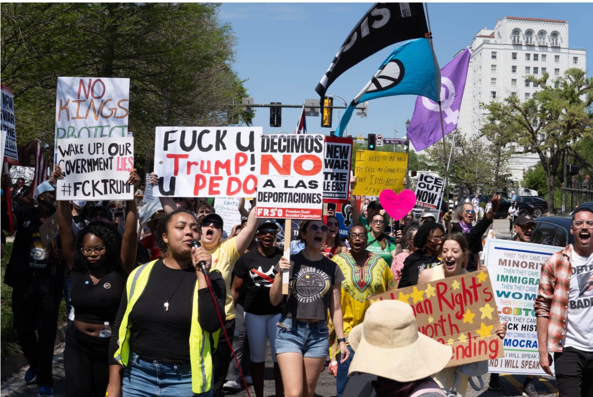 People in Baton Rouge march in the street with signs and flags.