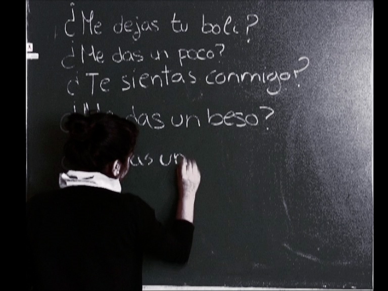 una chica escribe preguntas sobre una pizarra verde