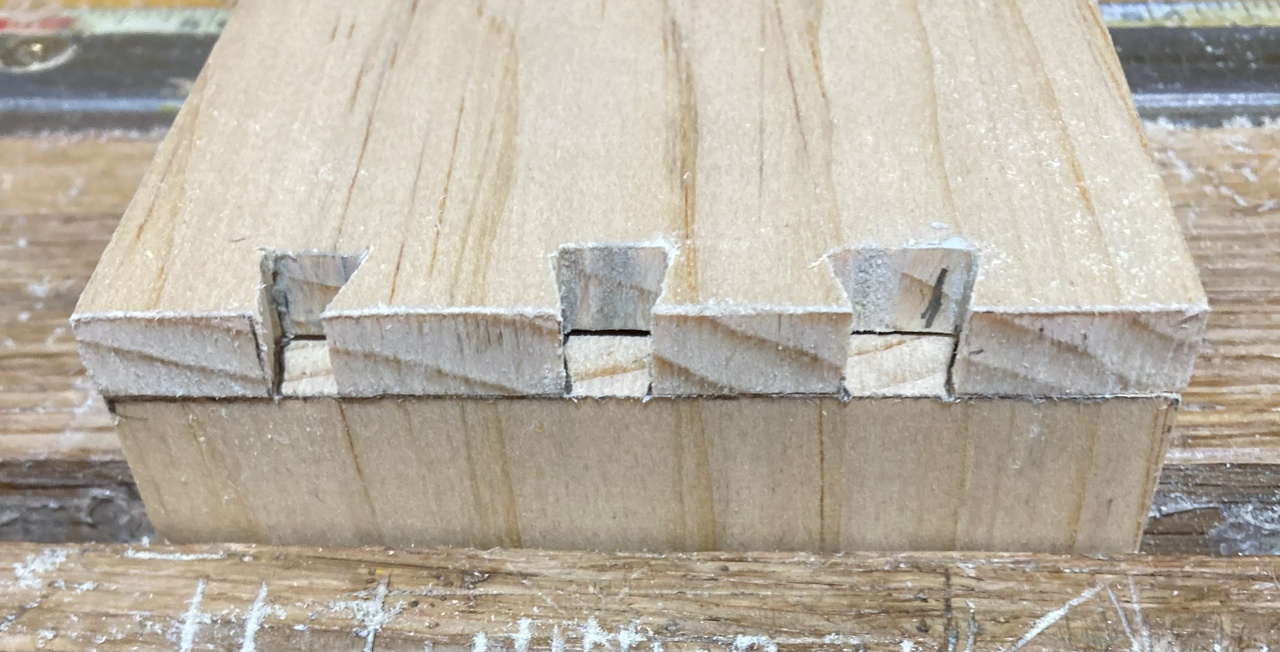 Transferring from the tail board to a pin board. The tail board has a "1" visible inside one of the tails, which will be matched to the pin board once it has been sawed and fit