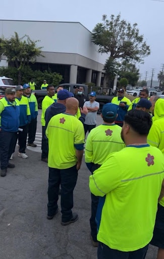 A group of workers meeting in a parking lot.