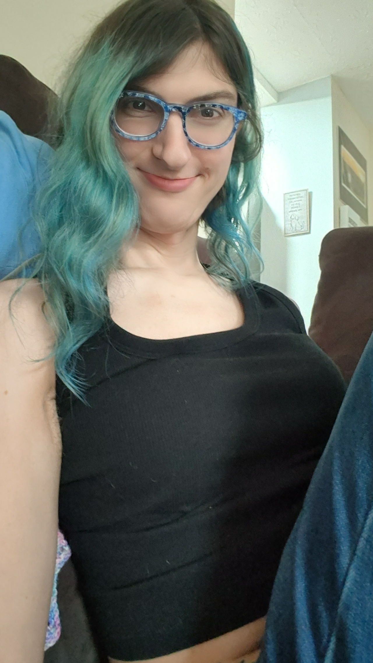 A white girl with wavy blue hair, glasses, and a black tank top.
