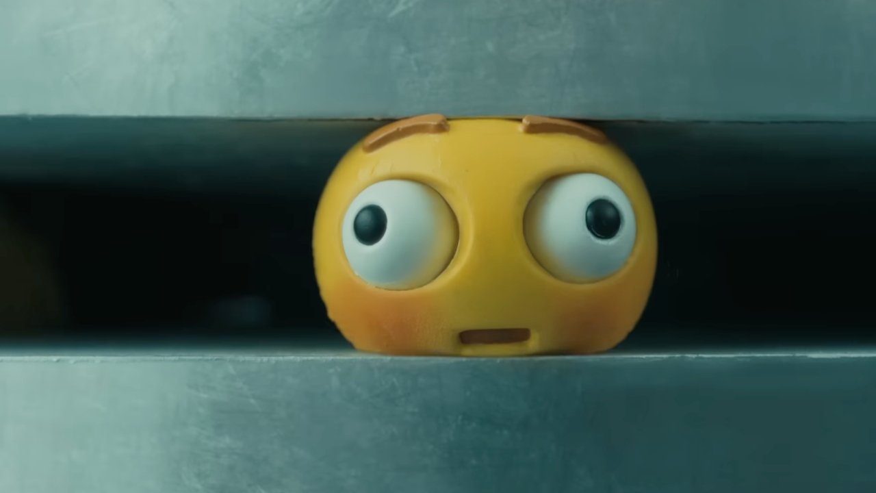 a still from the 2024 Apple CRUSH ad: a foam ball shaped like an emoji has its eyes bulging out of its sockets as it is squashed by a hydraulic press