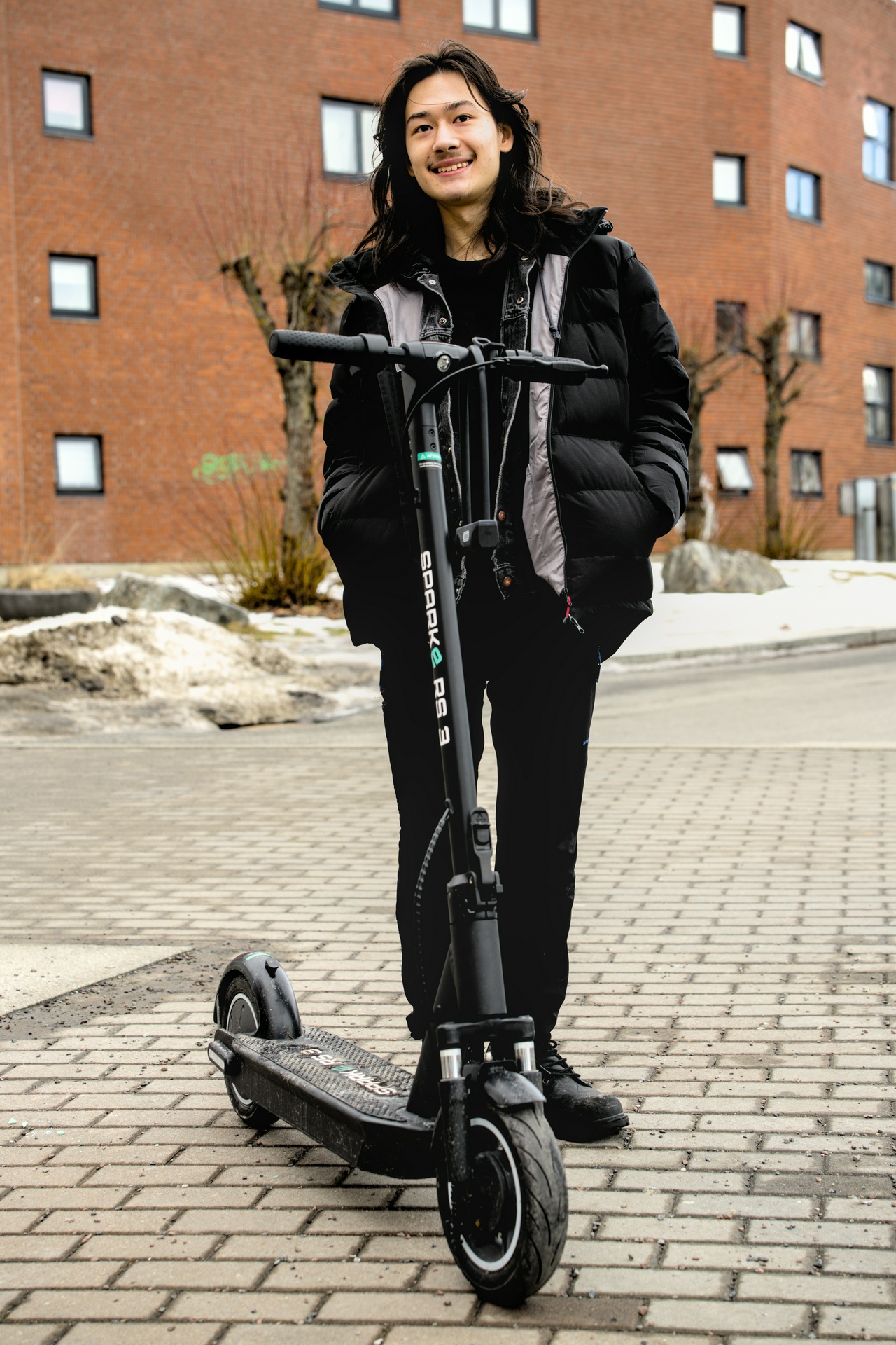 EN ung mann i svarte klær foran en svart ståsykkel