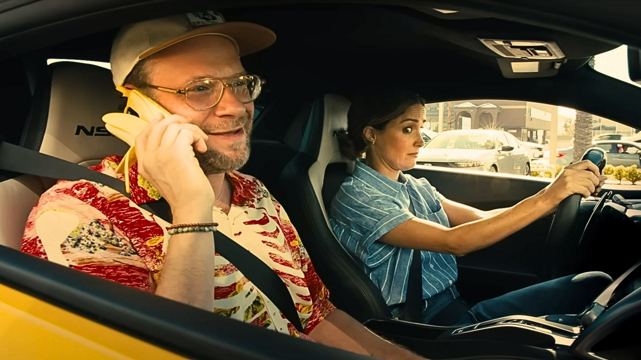 Seth Rogen takes a call on his banana phone while Rose Byrne judges from the driver's seat