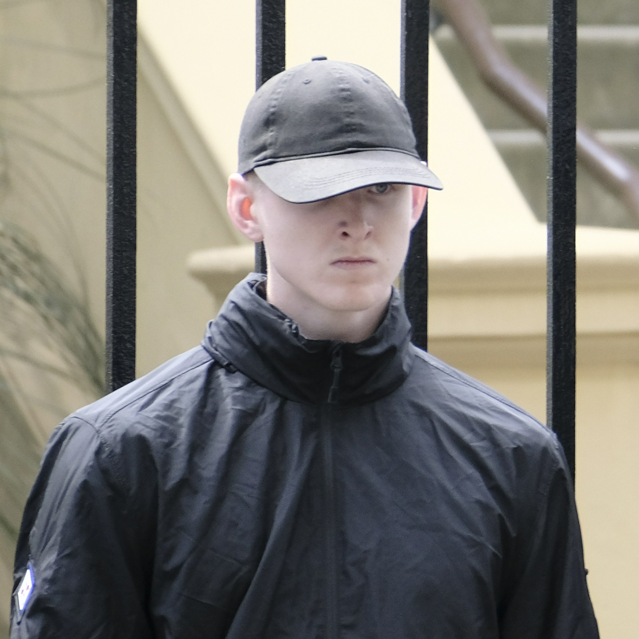 Very young white man with furious expression partly hidden by a black cap