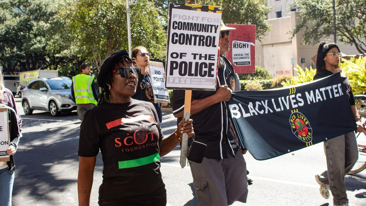 A group of protesters marching with signs and a banner.