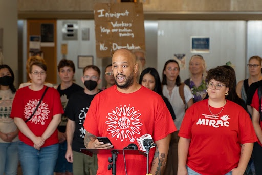  A group of people wearing red shirts holding a press conference.