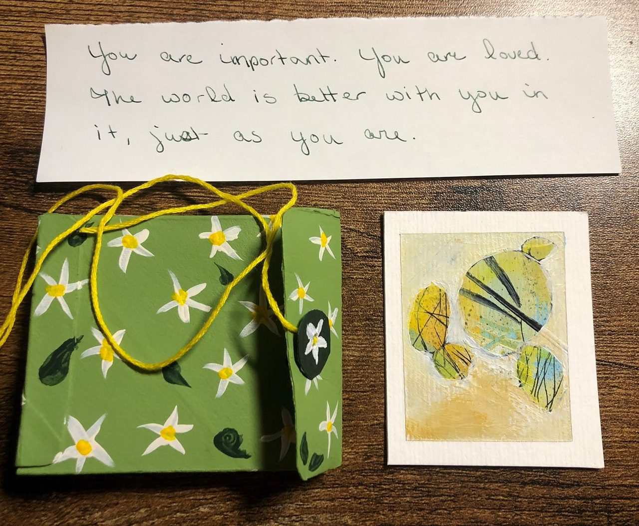 A box, a message, and a painting. a postage-stamp painting, a floral-painted box, and a very kind message for whomever opens the box.