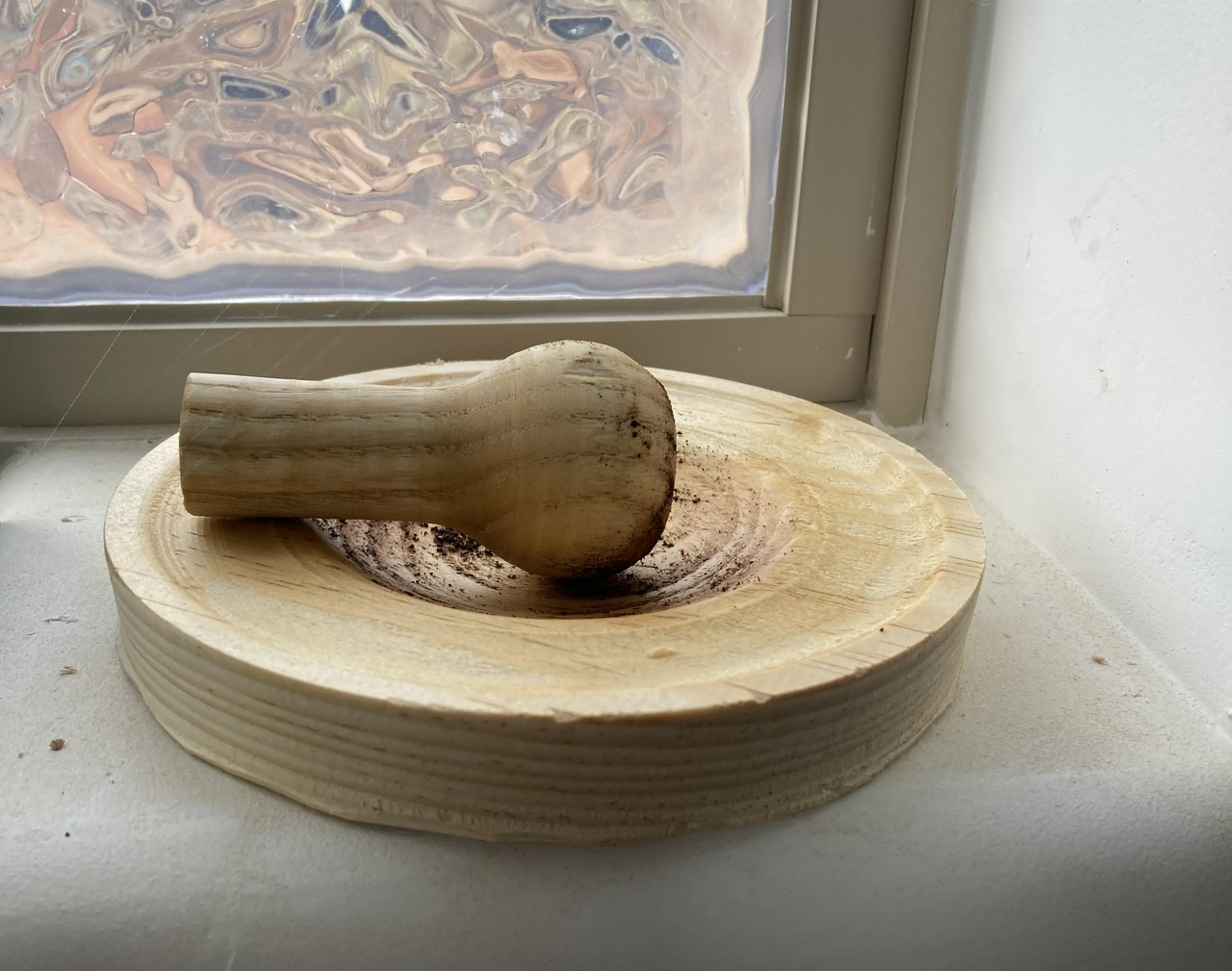 wooden mortar and pestle, viewed from the side, in front of a window