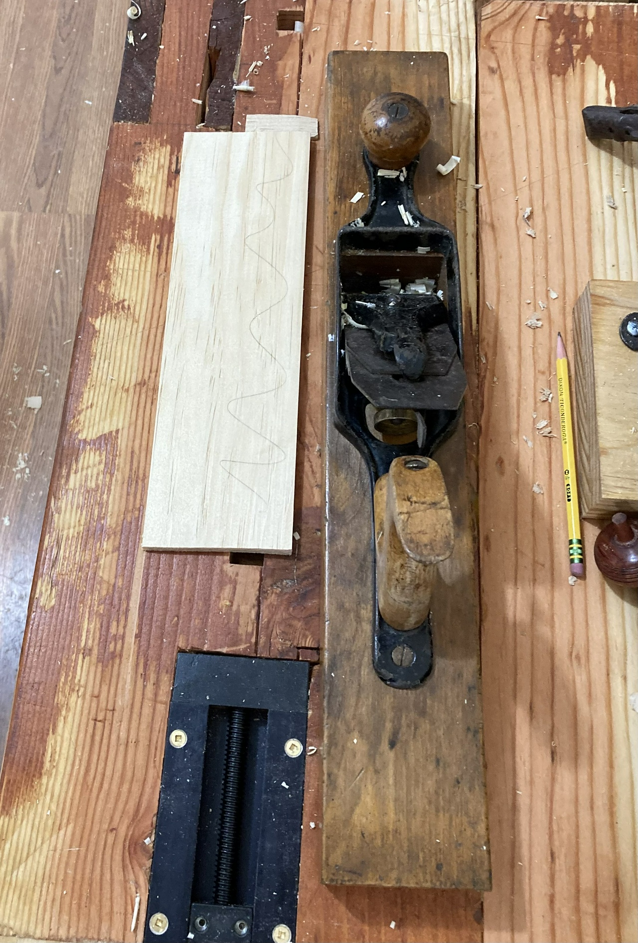 thin pine board in inset vise, with a transitional plane next to it; there is also a pencil