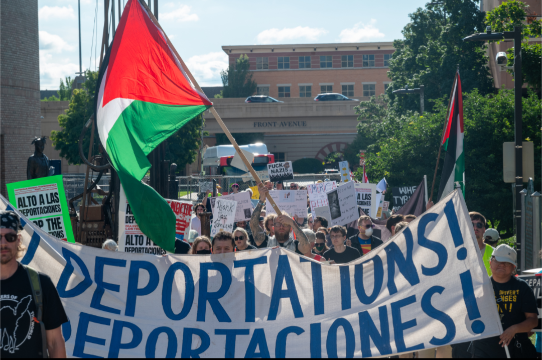 Protesters marching with flags and a banner.