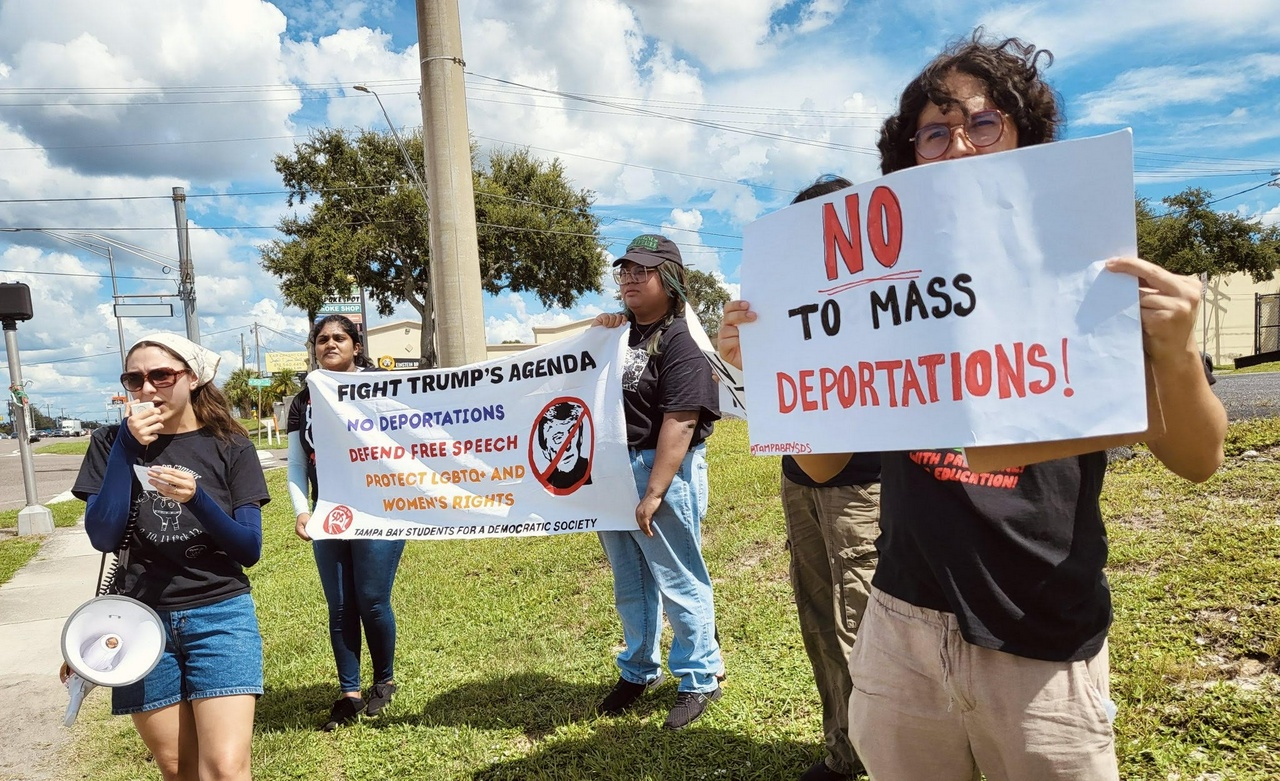 A group of students protest with a megaphone and hold signs that say, 