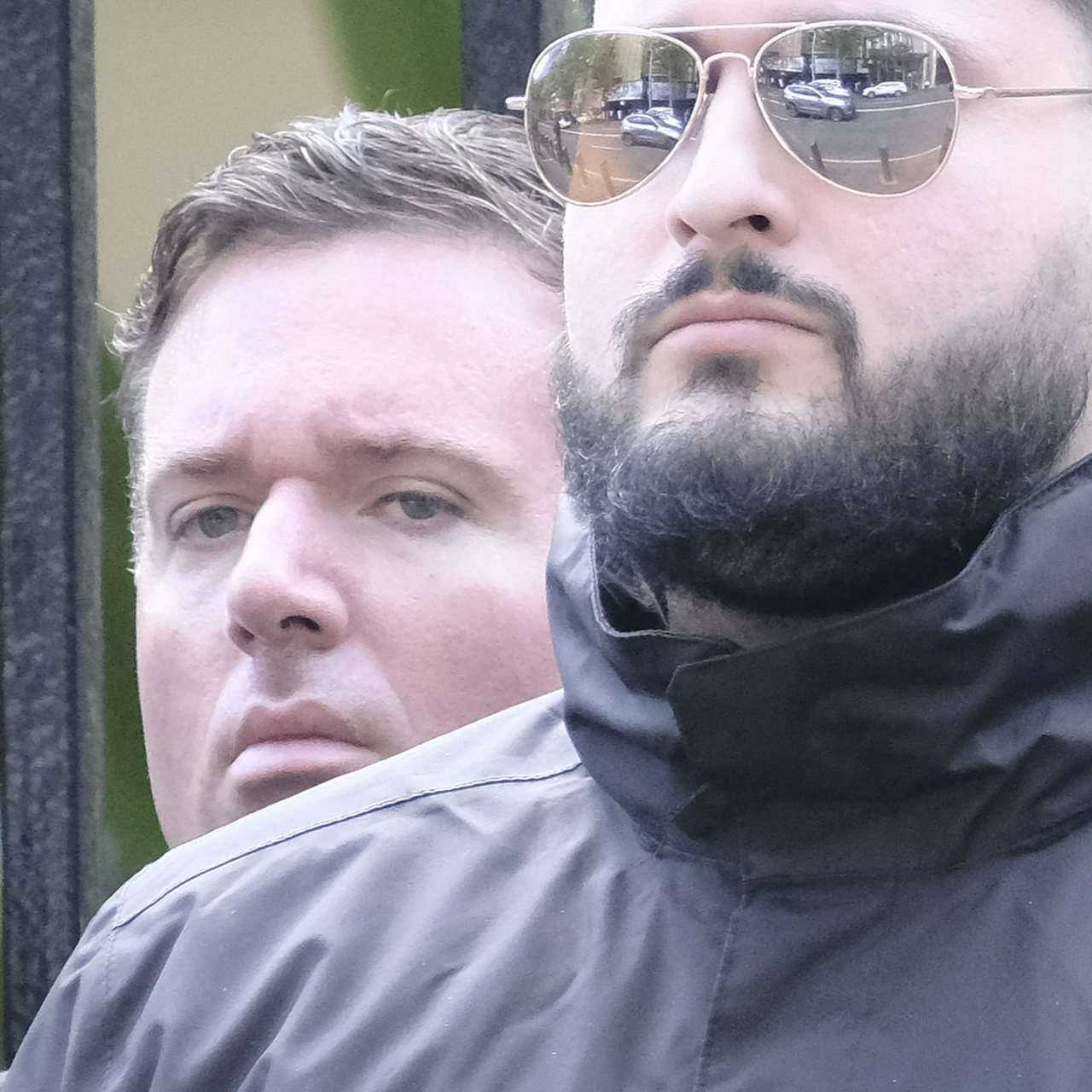 An older greying guy with drooping features, tall lips and gelled hair frowns over someone else's shoulder