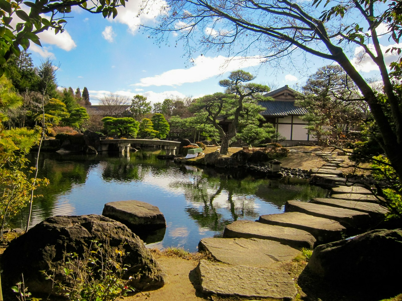 photo of a stone path crossing a brook and leading to a house, with another bridge in the background, by Junho Kwon