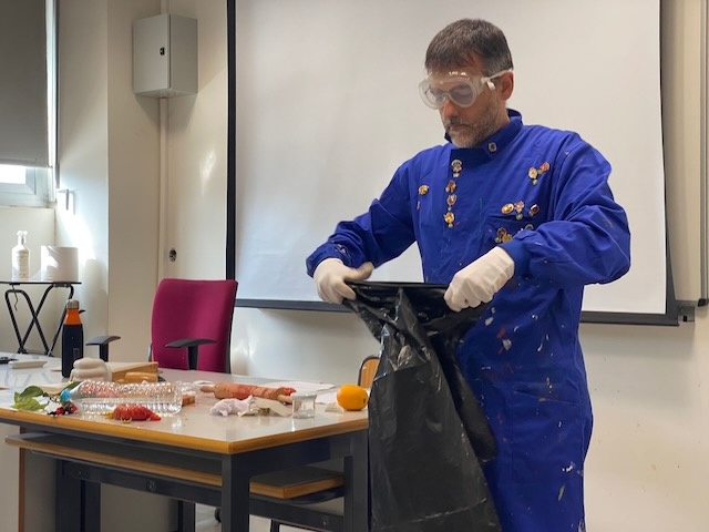 una persona en una performance con un mono azul y una bolsa de basura