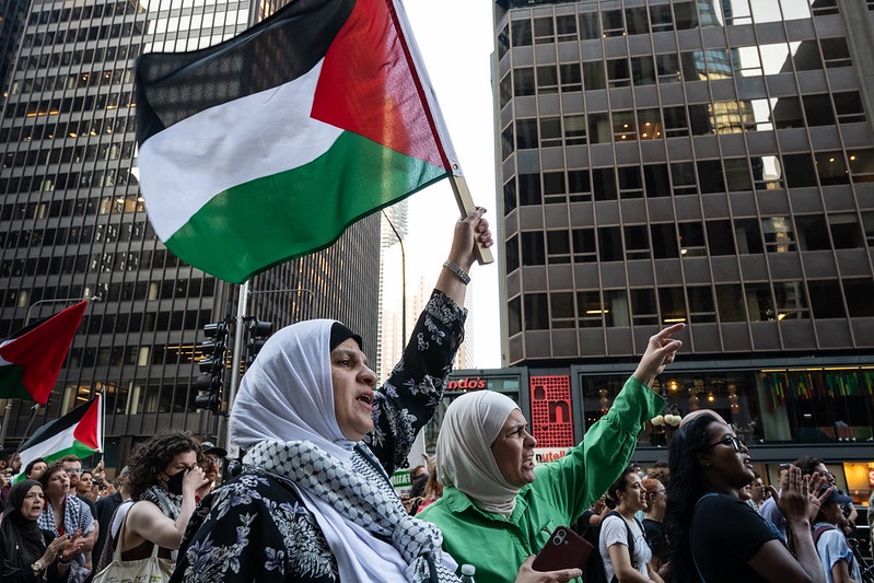 A march of protesters holding Palestinian flags.