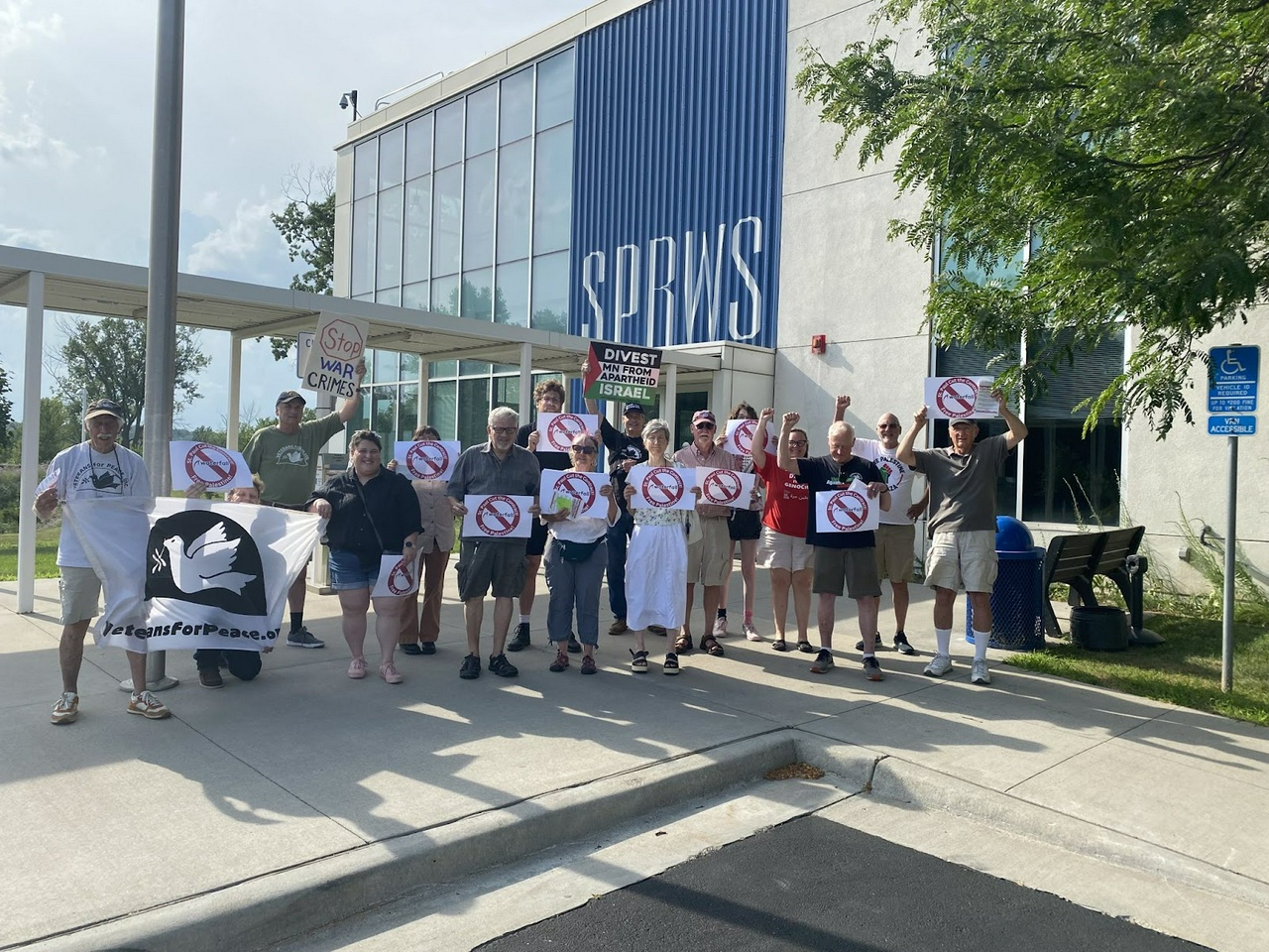 A group of protesters holding signs in front of a building.