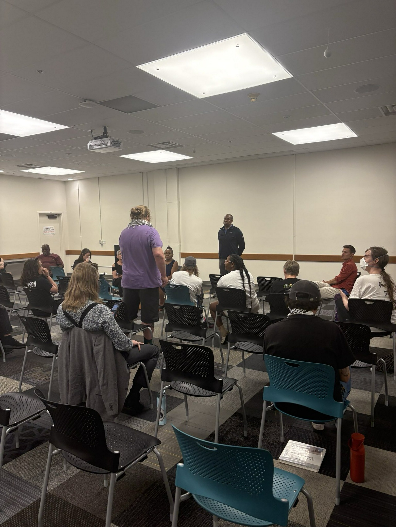 A classroom full of people listening to a person speaking.