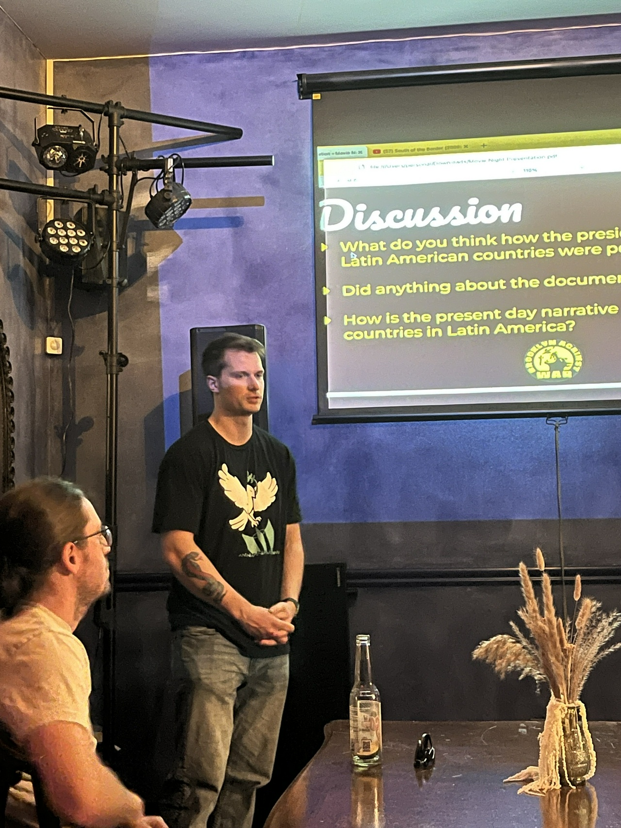 Brooklyn event against U.S. intervention in Venezuela. Man standing next to a projector screen that has questions for the audience on it