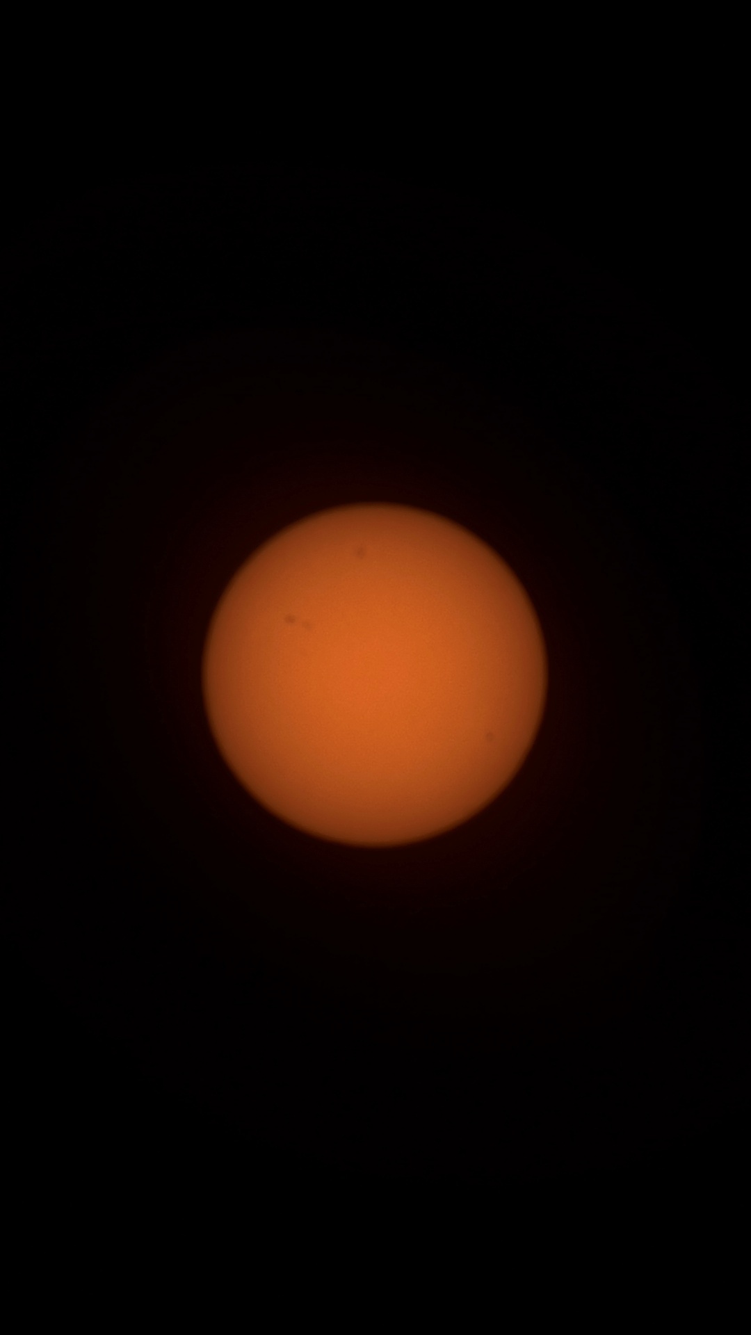 A close-up image of the sun showing a detailed and textured orange surface surrounded by darkness, highlighting sunspots and solar features.