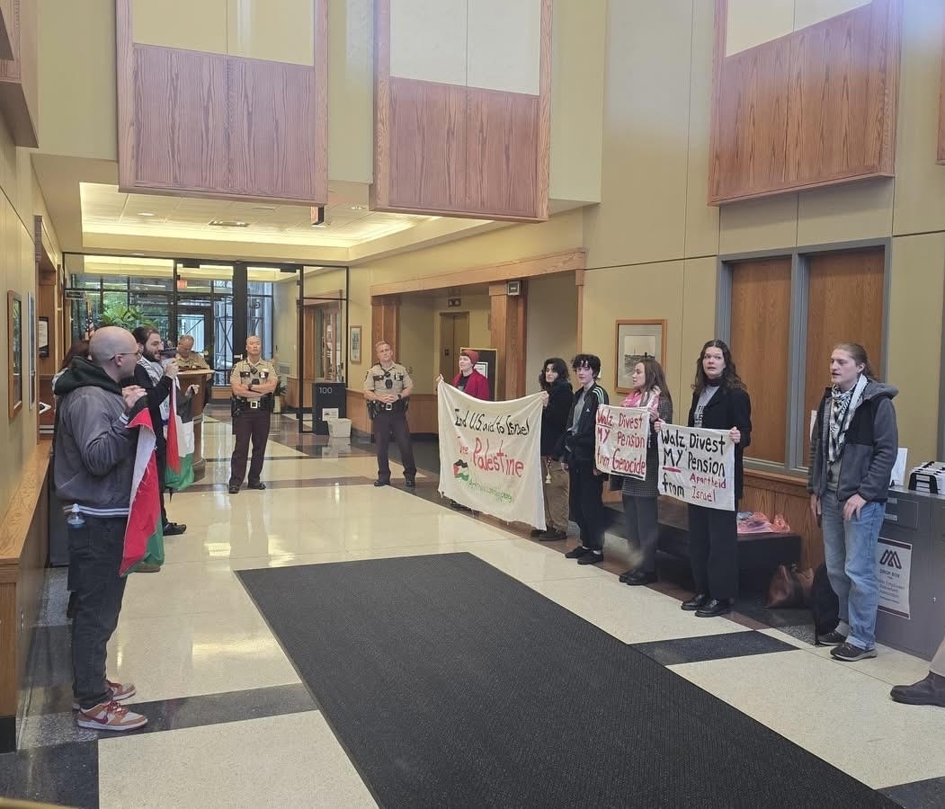 Divestment sit-in participants stare down state troopers inside the Minnesota Retirement Systems Building.  | Fight Back! News Divestment sit-in participants stare down state troopers inside the Minnesota Retirement Systems Building.