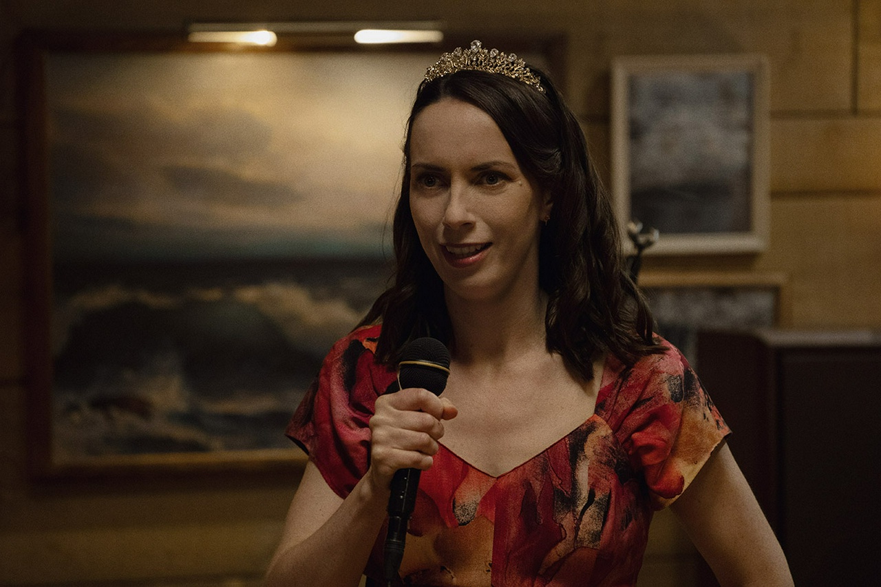 Patricia, hosting in a gold tiara and wielding a mic, is the belle of the ball at Sunset Cocktails