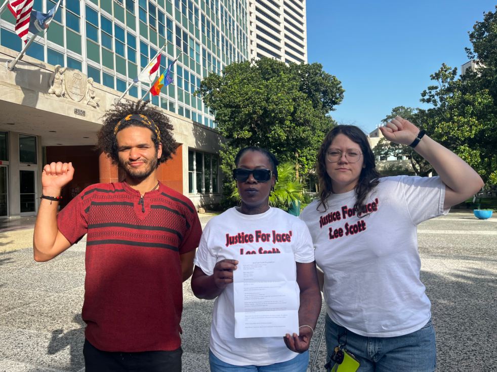 Shanta Scott, center, and supporters hold up a letter to the mayor in front of city hall before delivering it inside.
