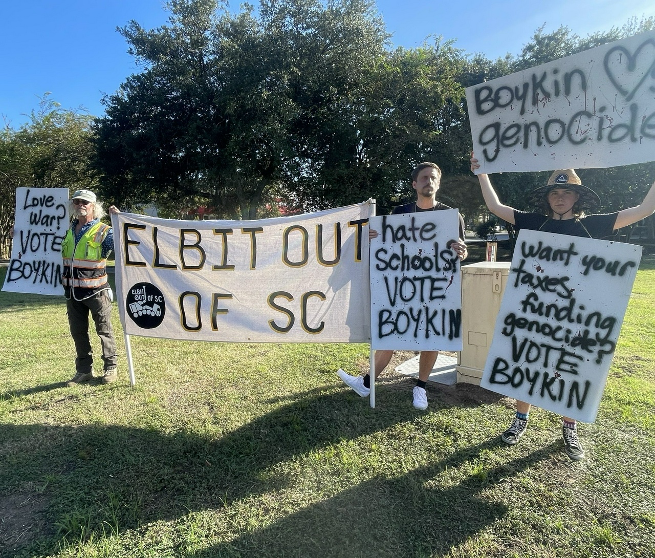 Protestors stand with signs that say Elbit out of SC