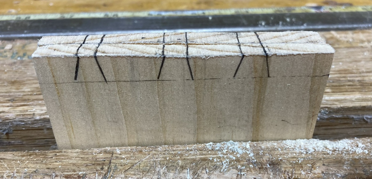 two boards held in a face vise, with marks for three dovetails on the boards