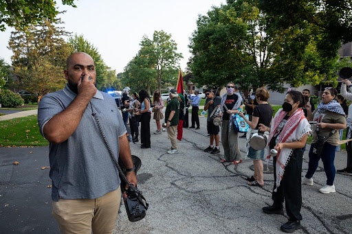 A man speaks to a group of protesters with a bullhorn.