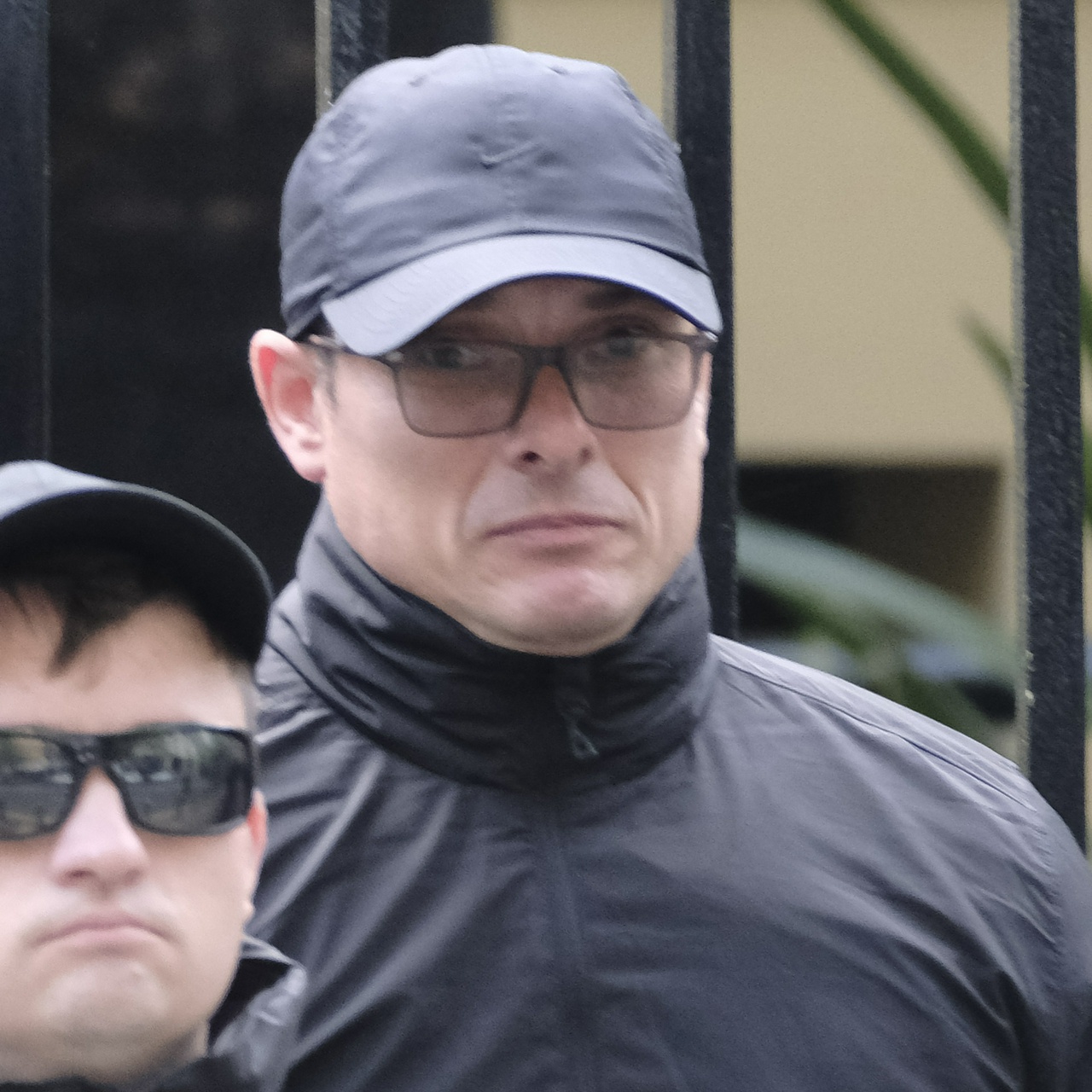 A very shocked-looking older man in polarised glasses and a black nike cap appears to be trying not to cry, and pulling his face down into his neck in the process