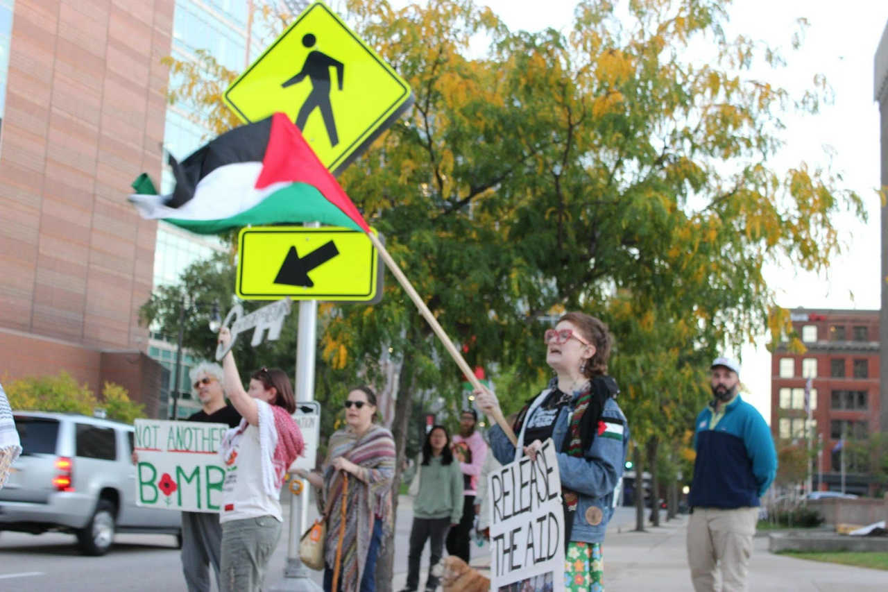 Protesters holding signs and a flag.