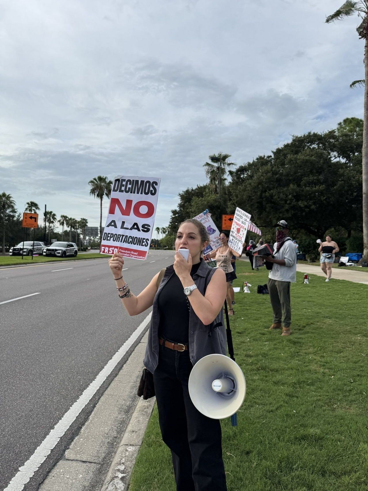 A woman standing with a sign and a megaphone.