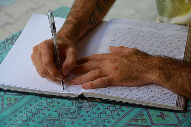 Hands writing in a paper notebook