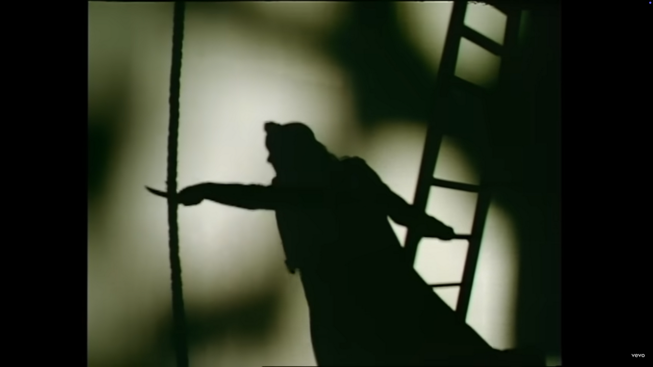 The Phantom's shadow is seen shaving away at a rope with a lil knife
