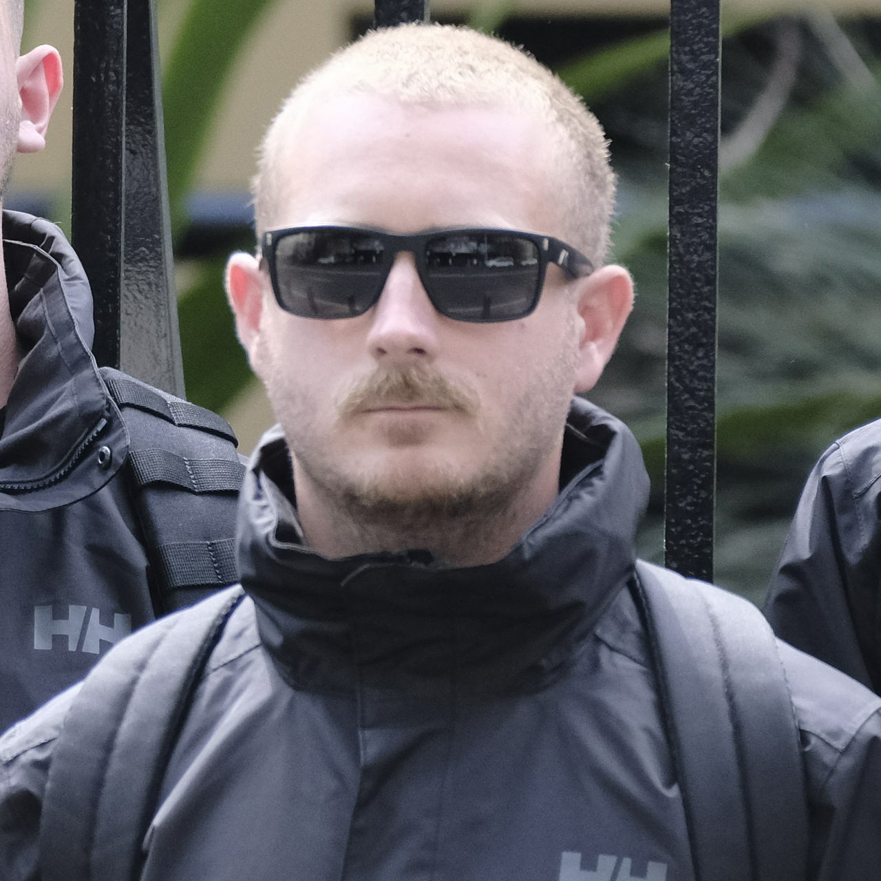 The same man from front on, his small mouth smirking under the whiskers