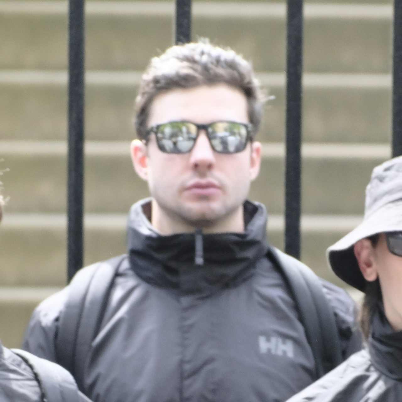 White man with curly black hair and very reflective sunglasses