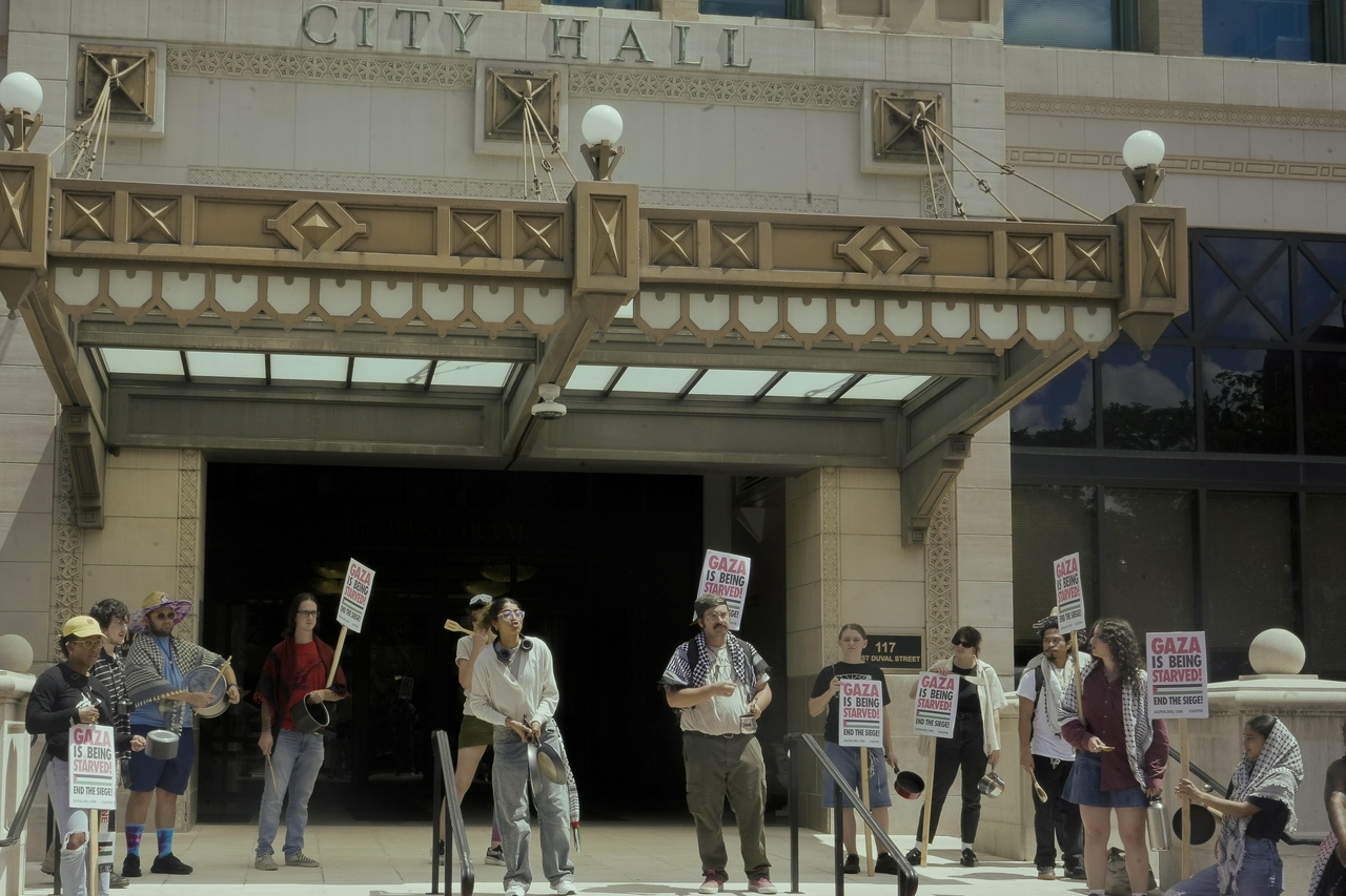 A group of protesters holding signs outside city hall.