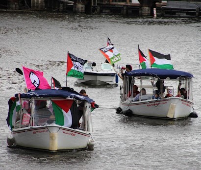Some boats move down the Milwaukee River displaying Palestine flags.