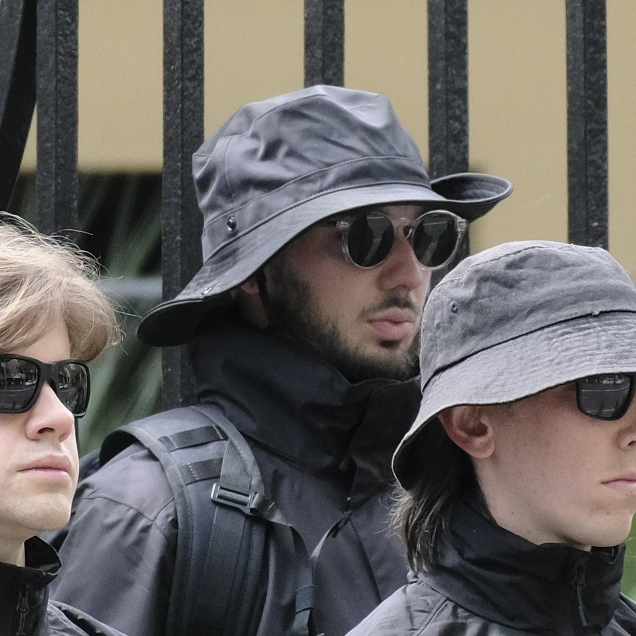 An ethnic man with dark black hair and full lips wearing round sunglasses with clear rims, and a floppy large bucket hat