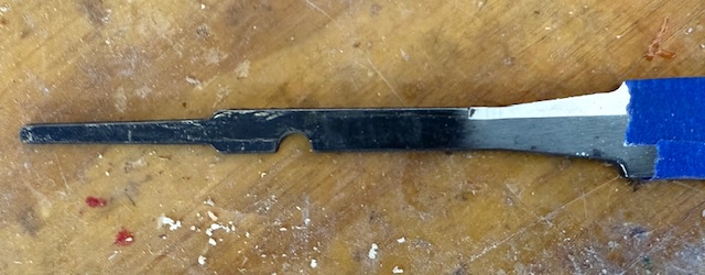 The tang of a carving knife, with the blade just visible, wrapped in blue tape