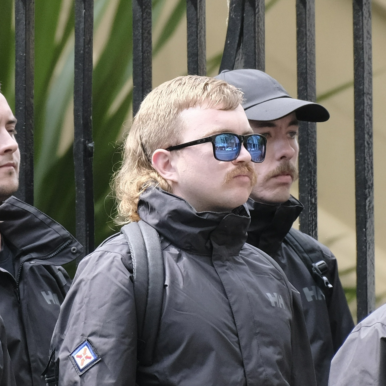 A stumpy ginger with a disjointed mullet, spiky moustache and reflective, chipped black sunglasses