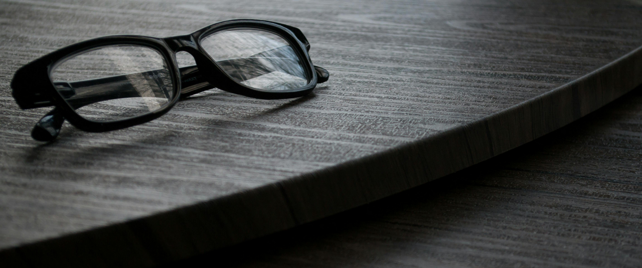 Image of black framed glasses on a black surface.